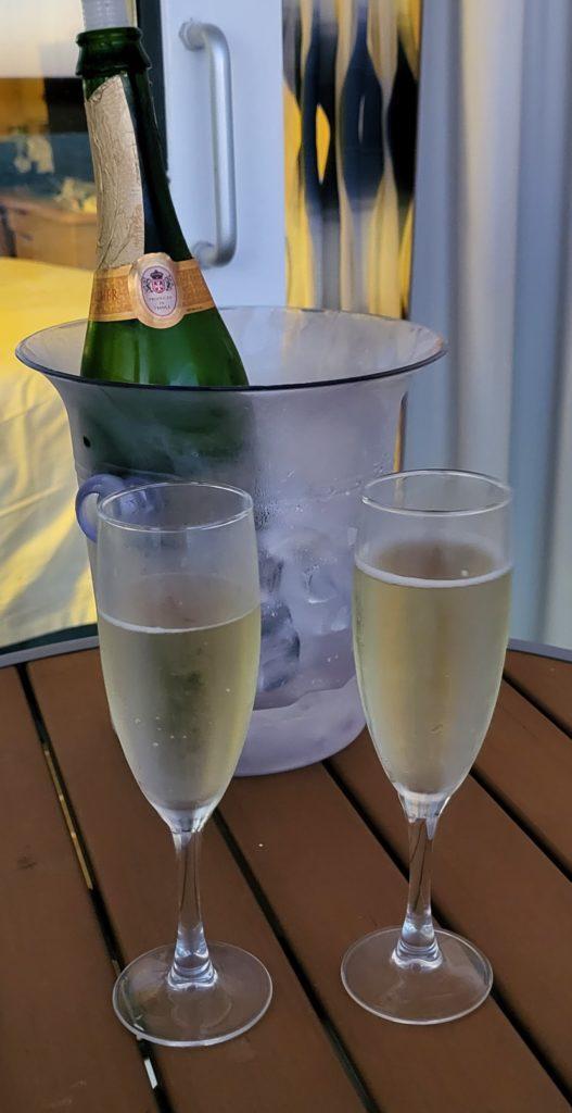 A bottle of champagne in a bucket of ice with two champagne flutes.