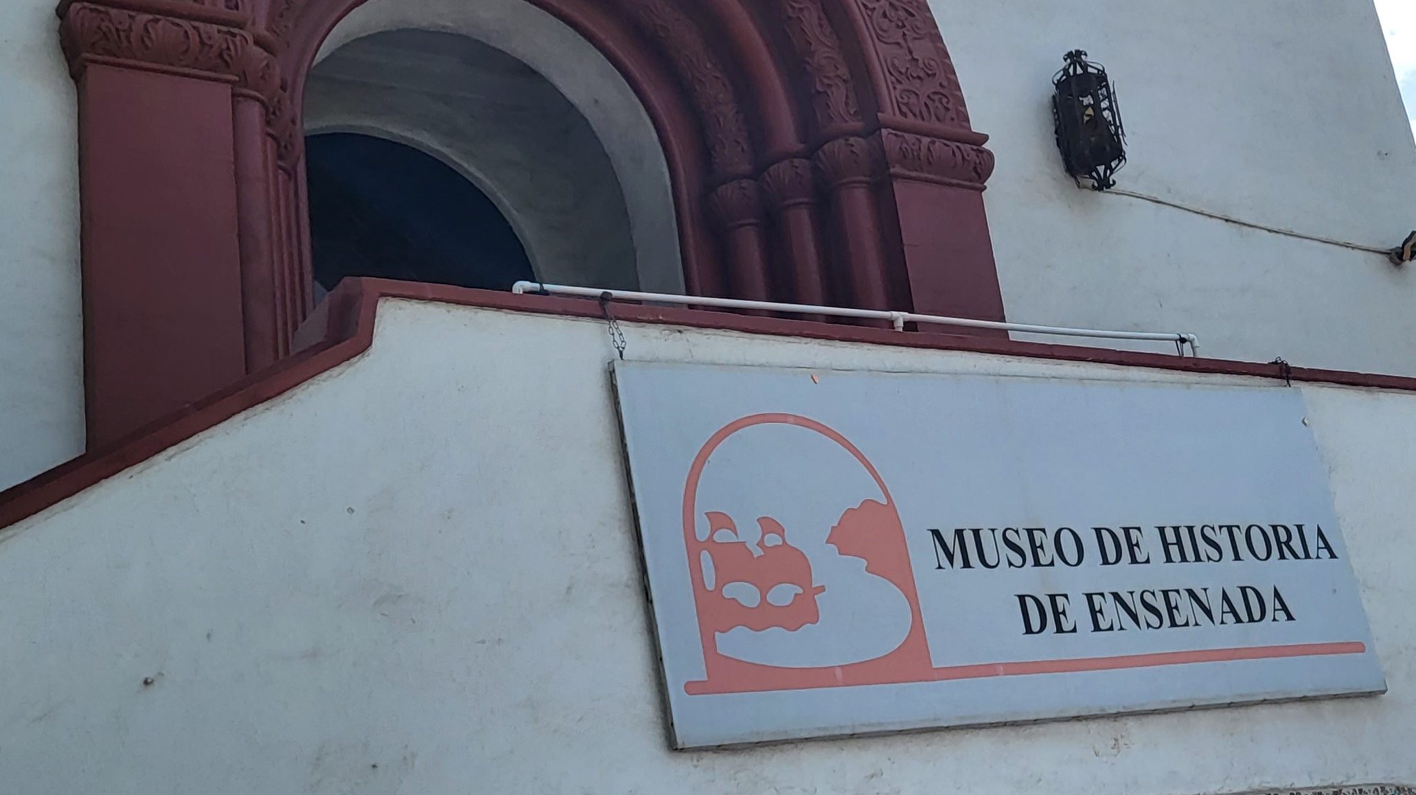 A sign in front of the entrance to the building reading "Museo de Historia de Ensenada."