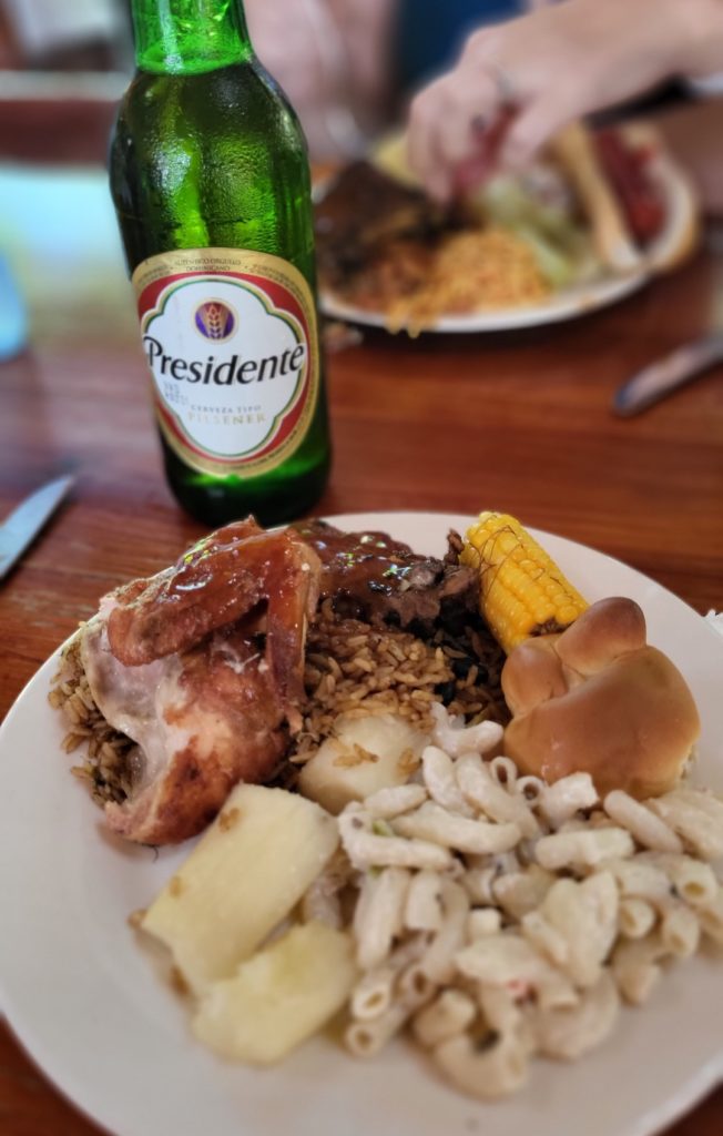 A plate of Dominican food and a tall bottle of Presidente beer.